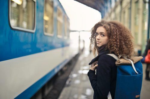 Chica joven a punto de coger un tren y mirando hacia atrás con aire melancólico