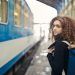 Chica joven a punto de coger un tren y mirando hacia atrás con aire melancólico